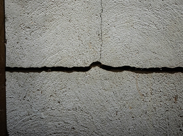 Close-up of a significant crack in a concrete foundation wall, illustrating potential foundation damage.