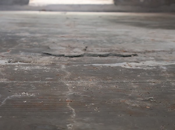 Concrete floor with a wide, spreading crack indicating foundation settlement.
