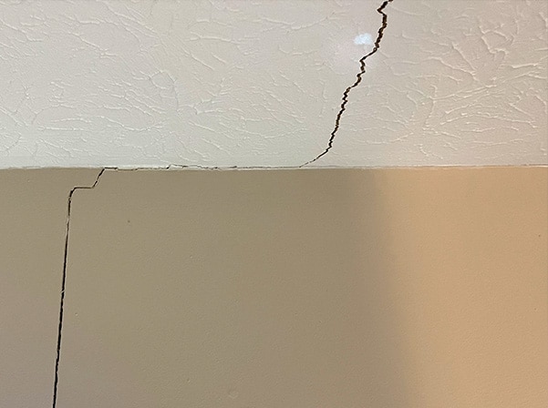 Large, jagged ceiling crack and wall junction indicating potential foundation movement.