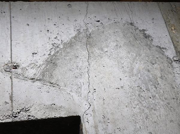 Close-up of a cracked concrete floor and wall, illustrating foundation issues and potential structural concerns.