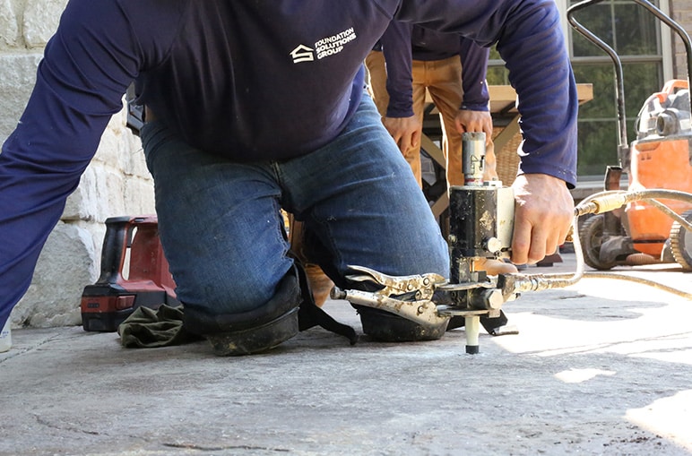 Foundation Solutions Group technician installing helical piers for long-term foundation stabilization.