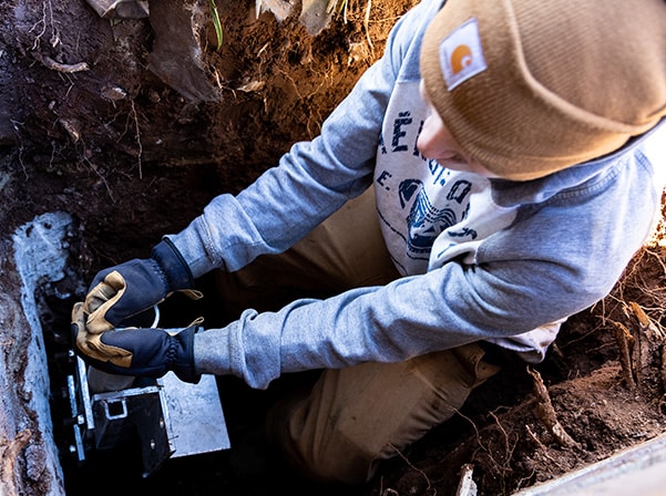 Foundation repair technician installing helical pier for stabilization and structural support.